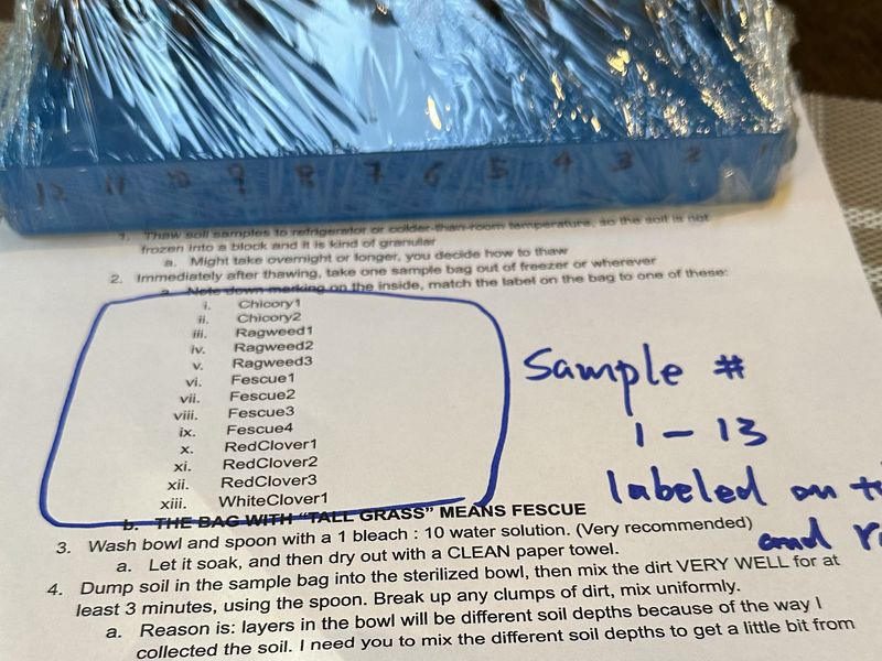A shrink-wrapped blue rack of numbered sample tubes resting on a
                  printed handling protocol, whose list of sample names has been
                  ringed in blue pen and annotated by hand.
